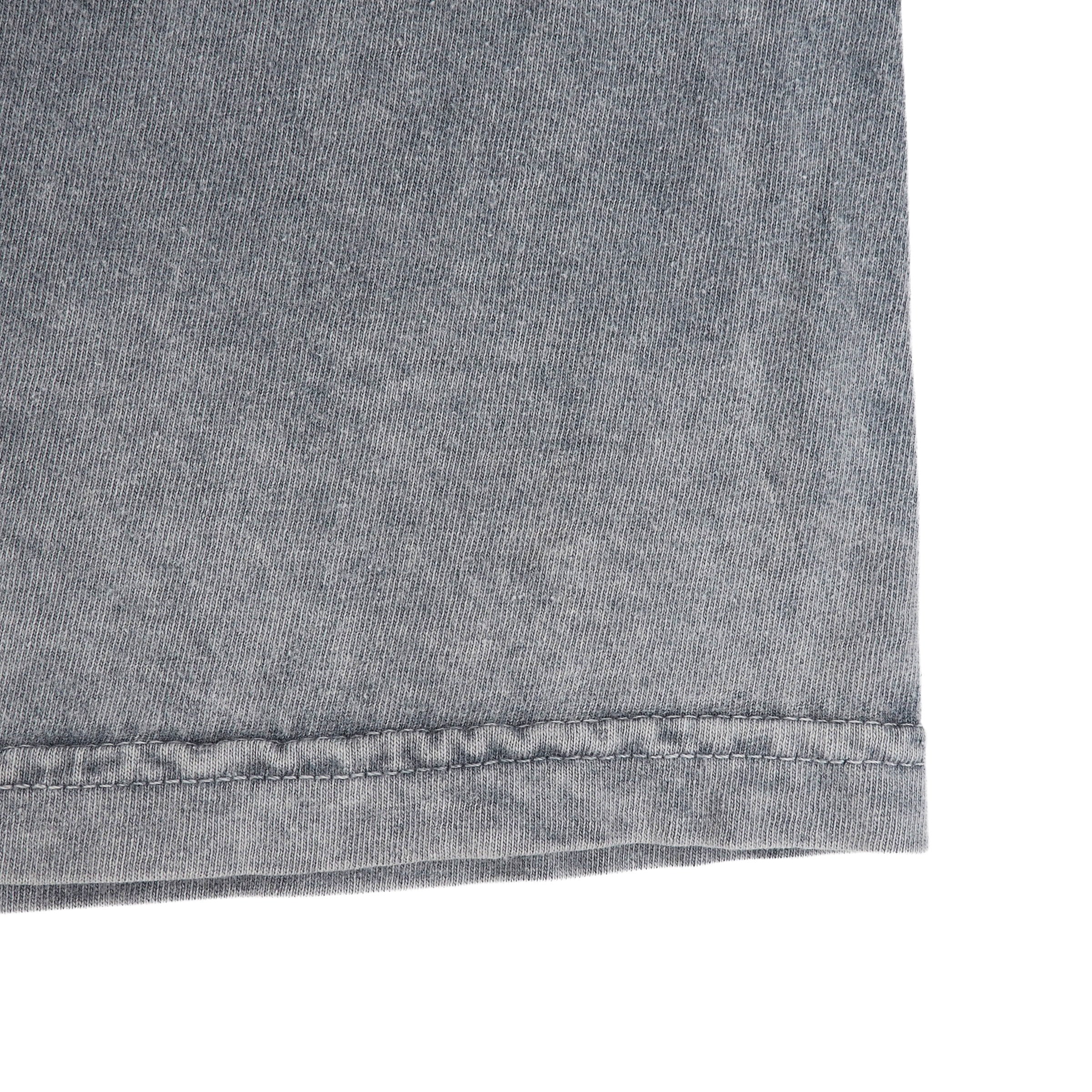 Close up of the hem of a grey t-shirt on a white background.