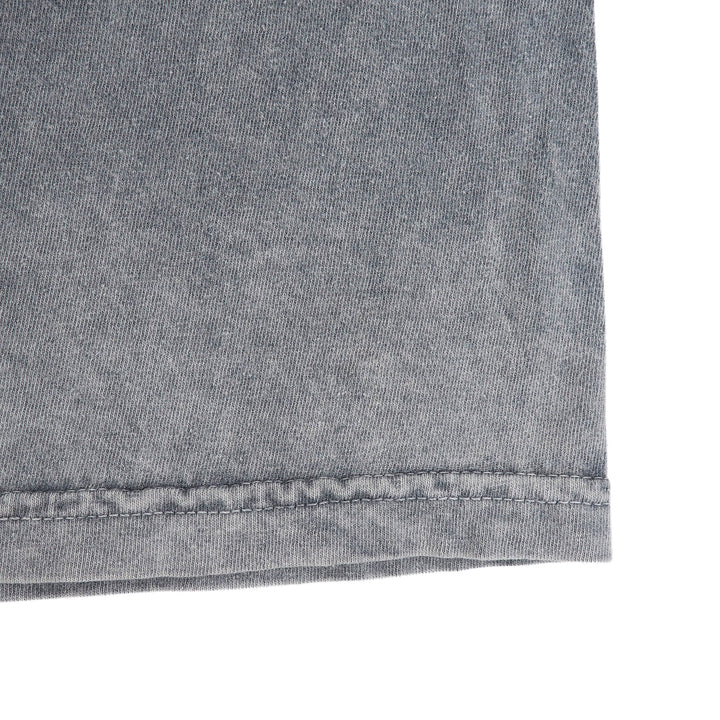 Close up of the hem of a grey t-shirt on a white background.