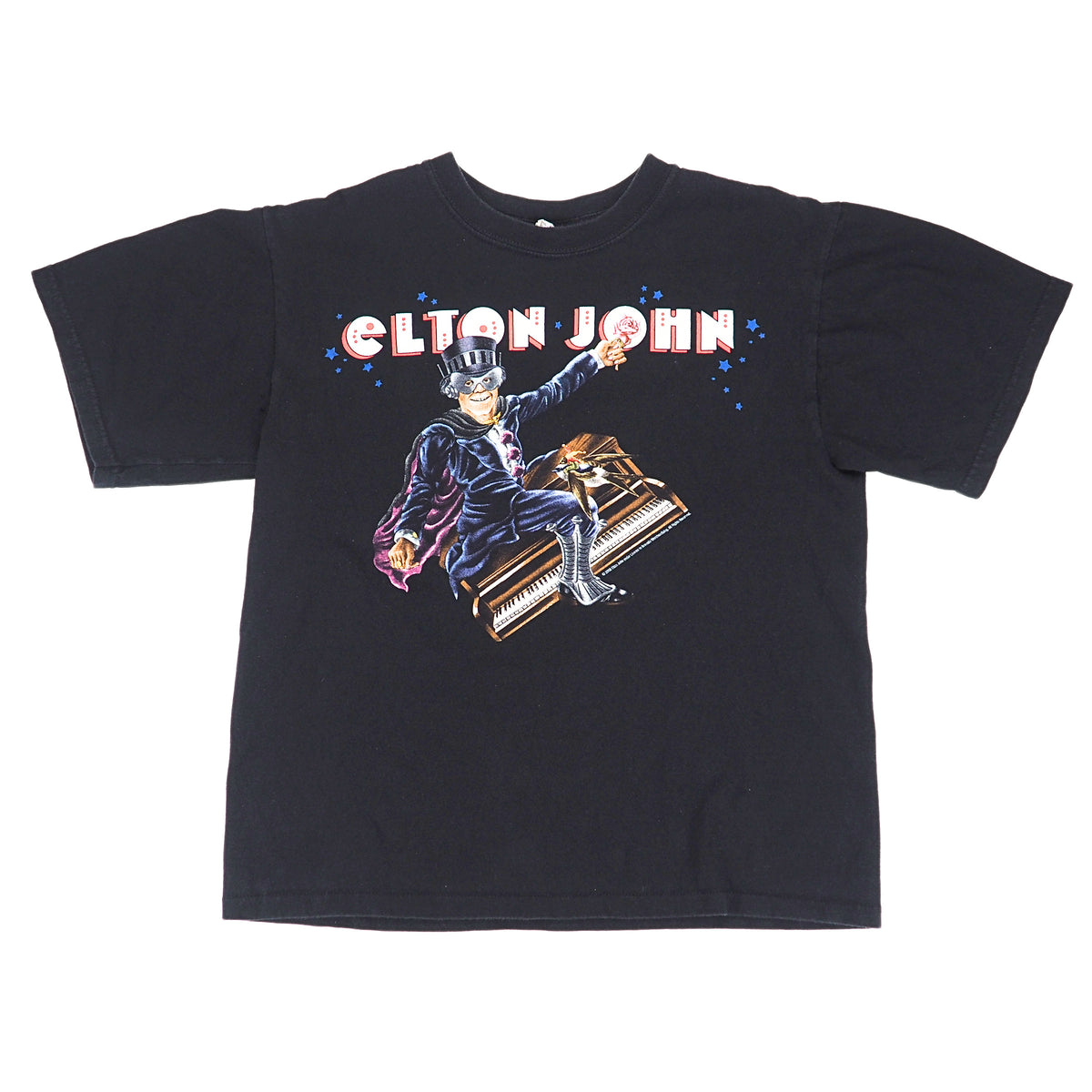 A black short-sleeve graphic t-shirt featuring a colorful print of Elton John riding a piano, with 'ELTON JOHN' written in red and white letters above the graphic.