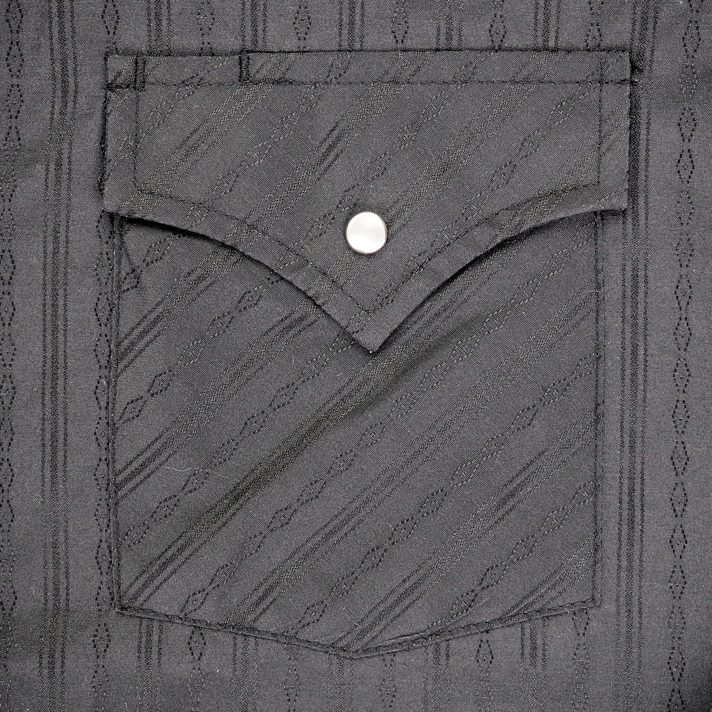 Close up of the pocket of a black shirt with subtle woven pattern.