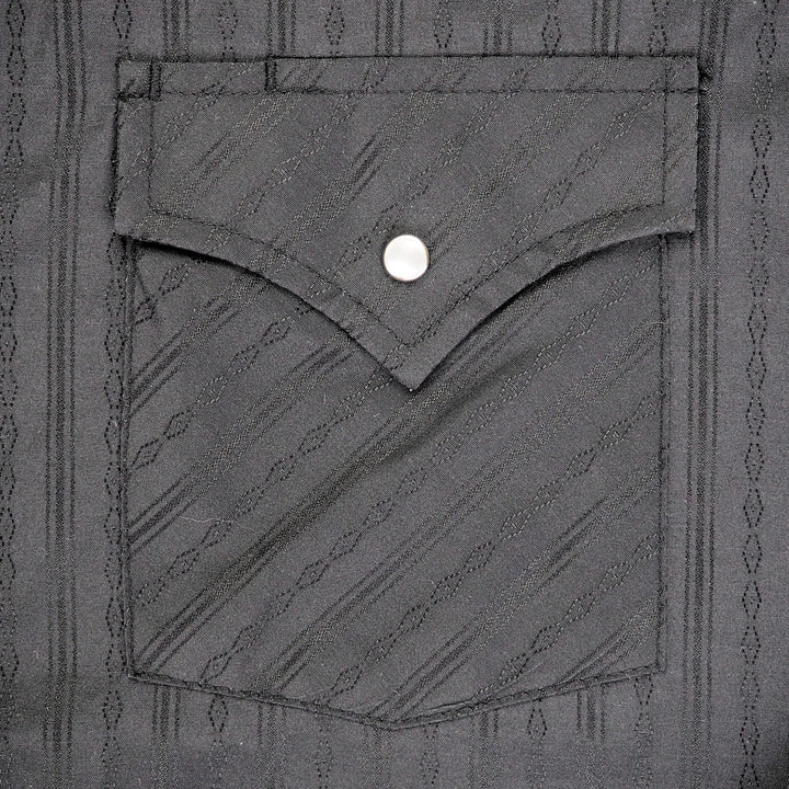 Close up of the pocket of a black shirt with subtle woven pattern.