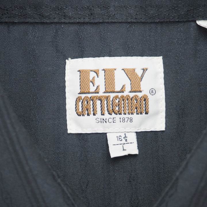 Close up of brand tag reading 'Ely Cattleman Since 1878' on the inside collar of a black shirt.