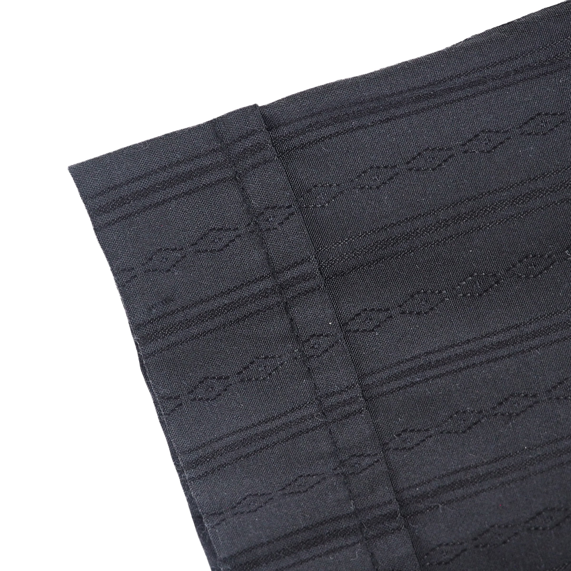 Close up detail of sleeve cuff of a black shirt with subtle stripes and diamond pattern.