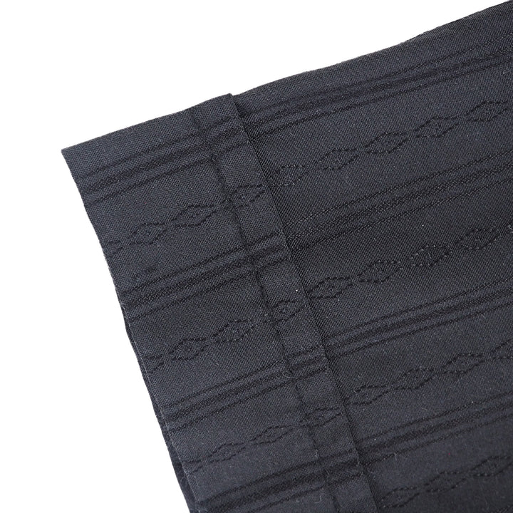 Close up detail of sleeve cuff of a black shirt with subtle stripes and diamond pattern.
