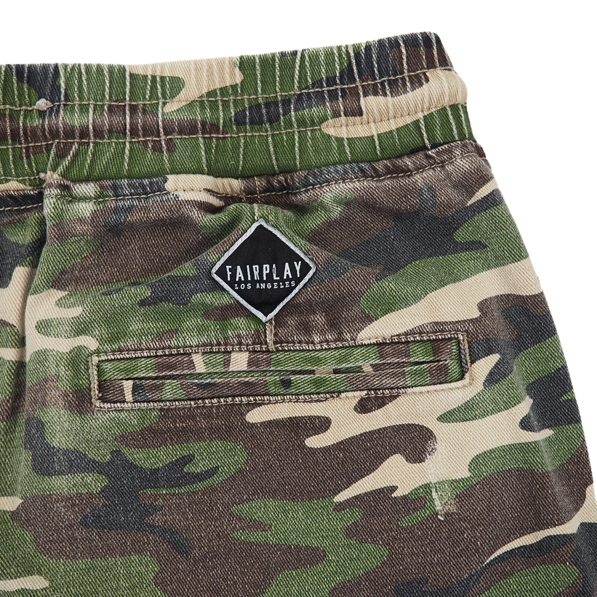 Detail of Camouflage pants waistband  with a Fairplay Los Angeles brand logo and pocket on a white background