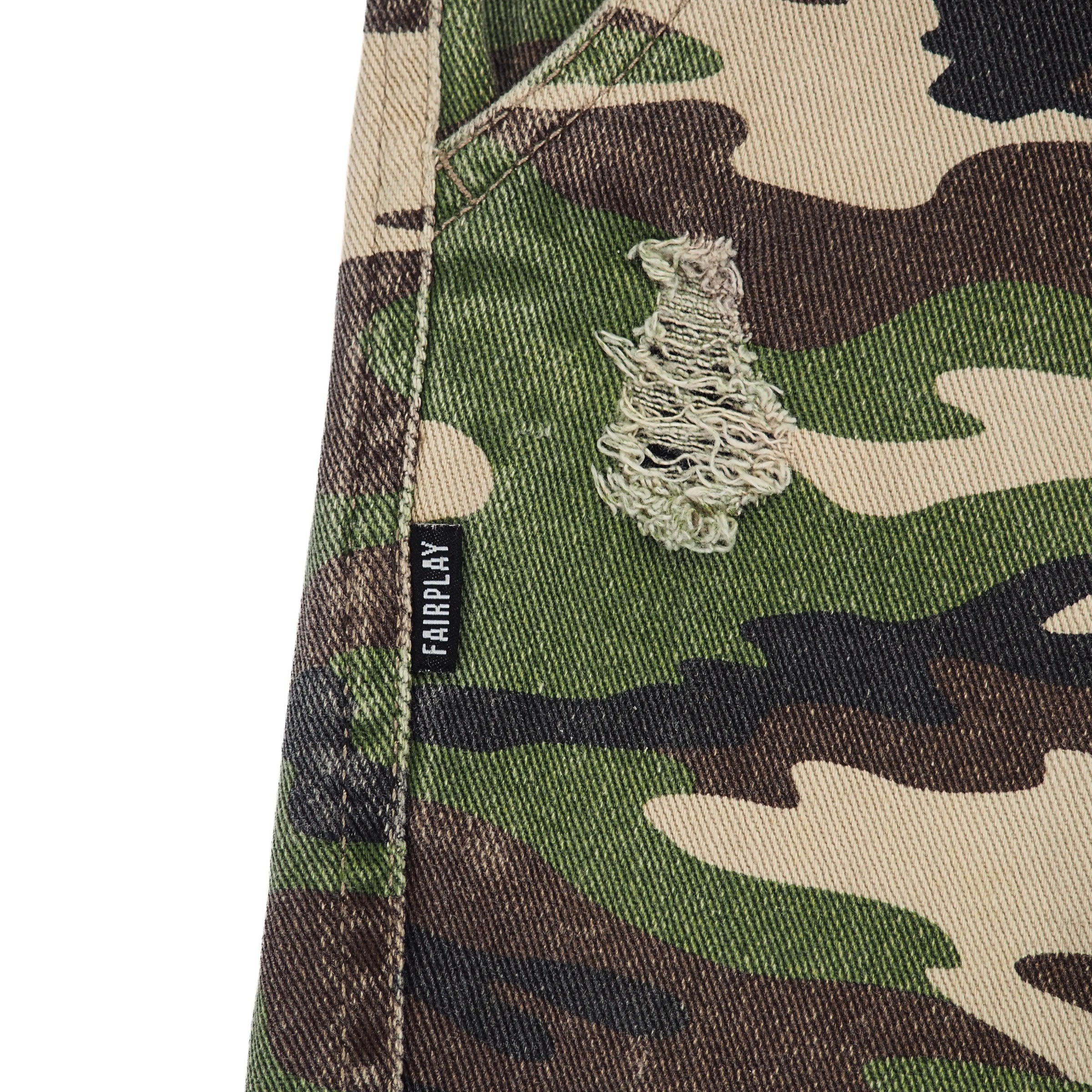 Close-up of a camouflage pants seam with a visible Fairplay brand label on a white background