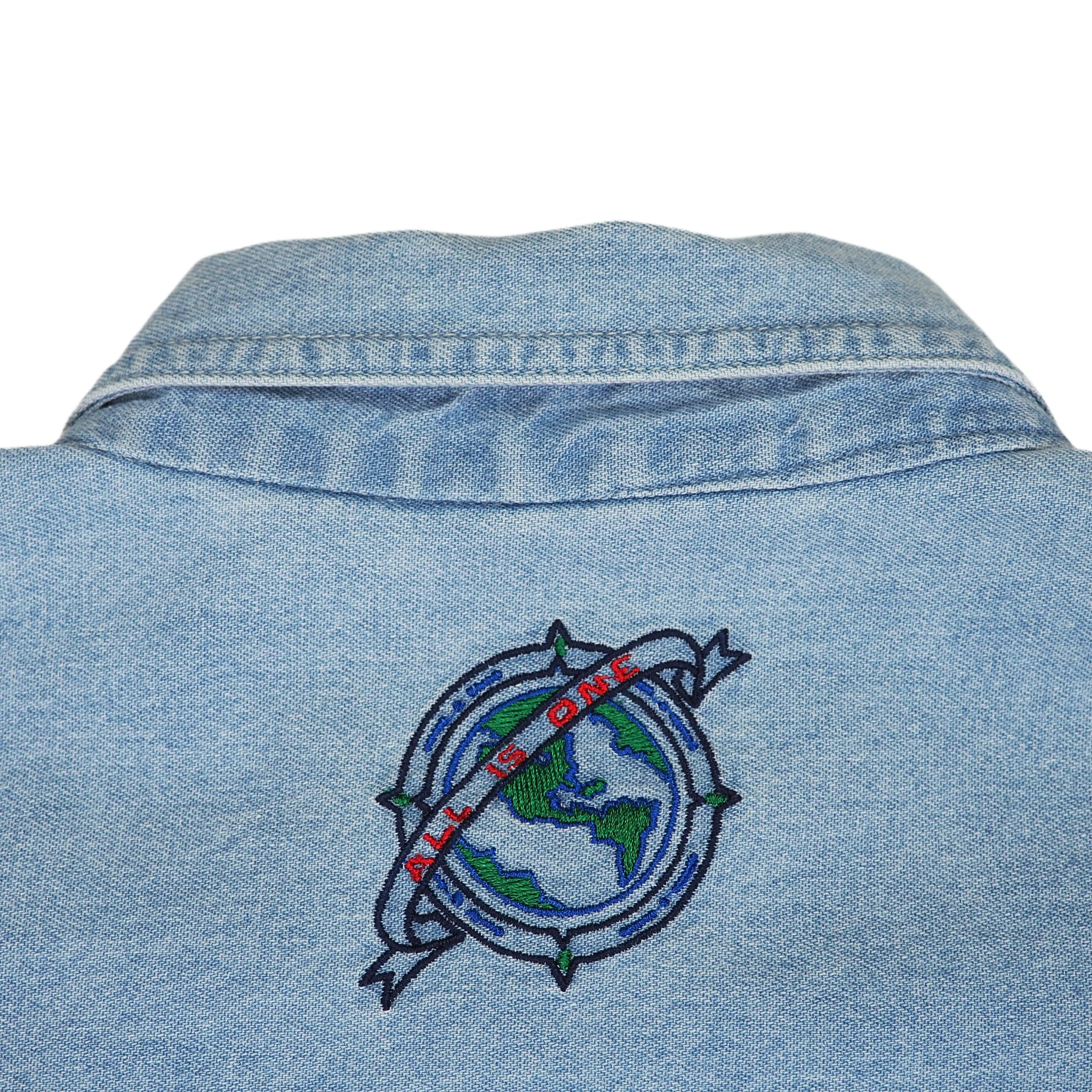 Blue denim shirt with embroidered 'All Is One' globe design on a white background