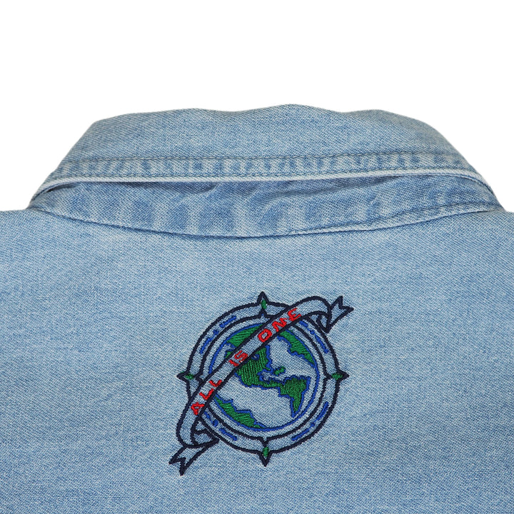 Blue denim shirt with embroidered 'All Is One' globe design on a white background