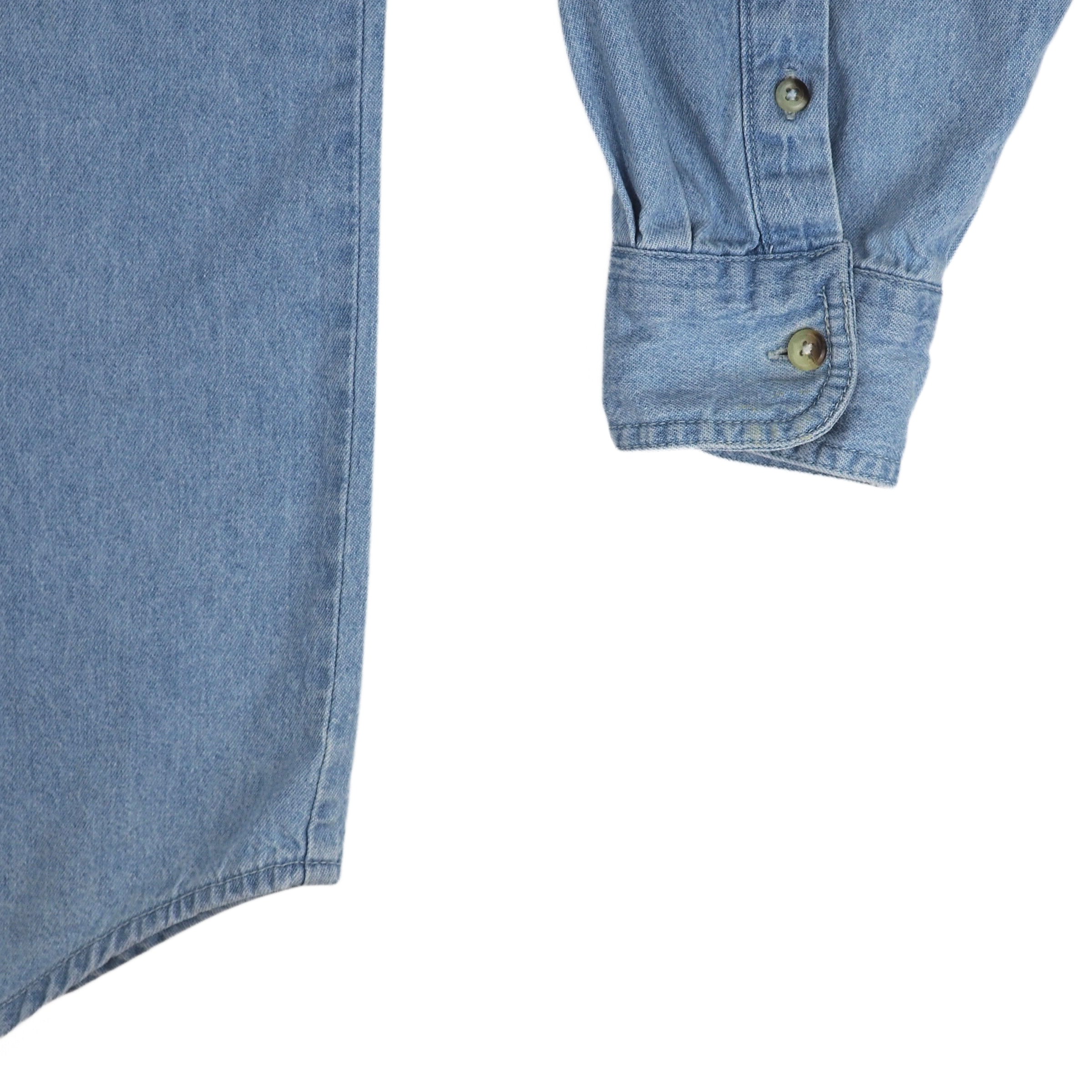 Close-up of a blue denim shirt tail and sleeve cuff with buttons on a white background