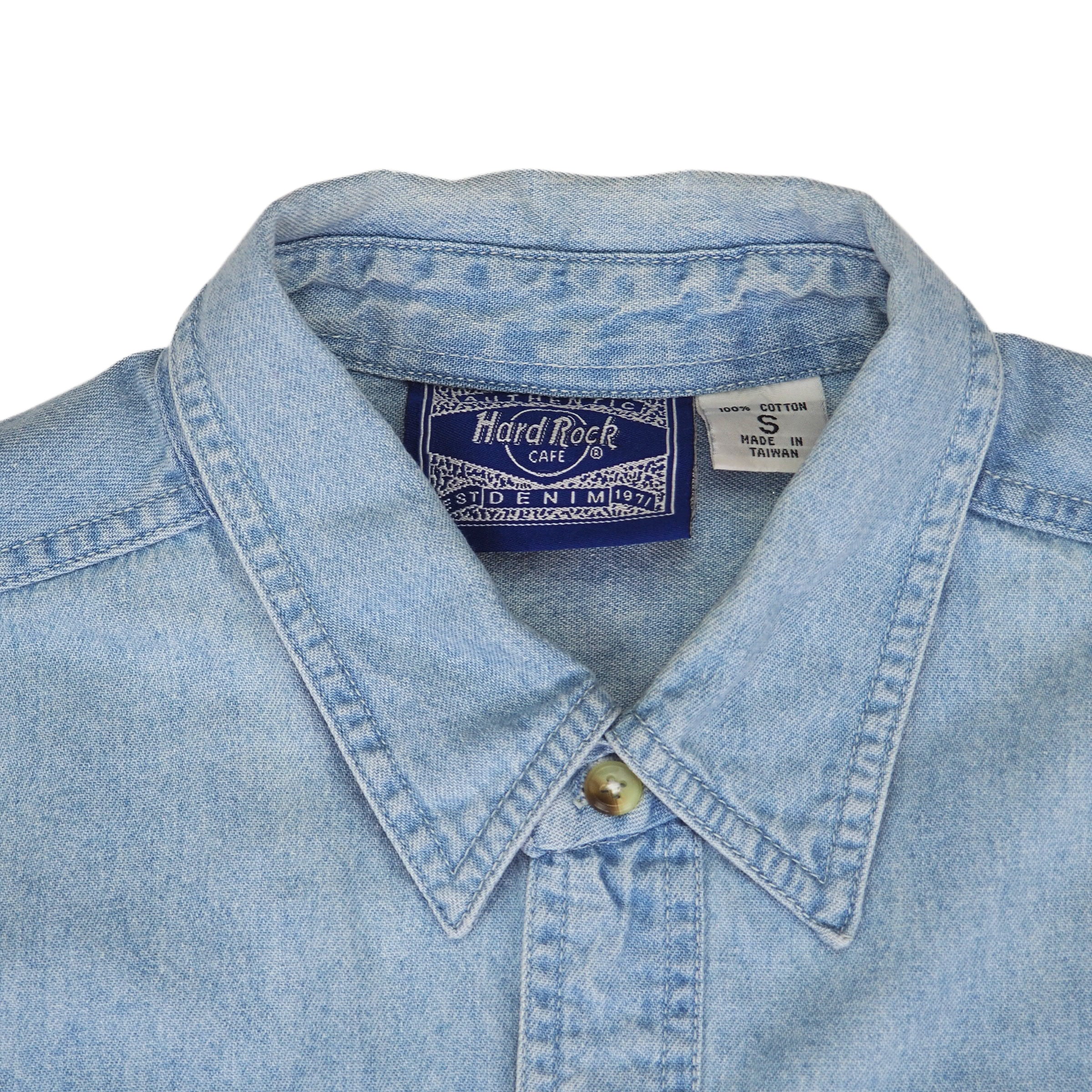 Close-up of a denim shirt collar with a Hard Rock Cafe brand label on a white background