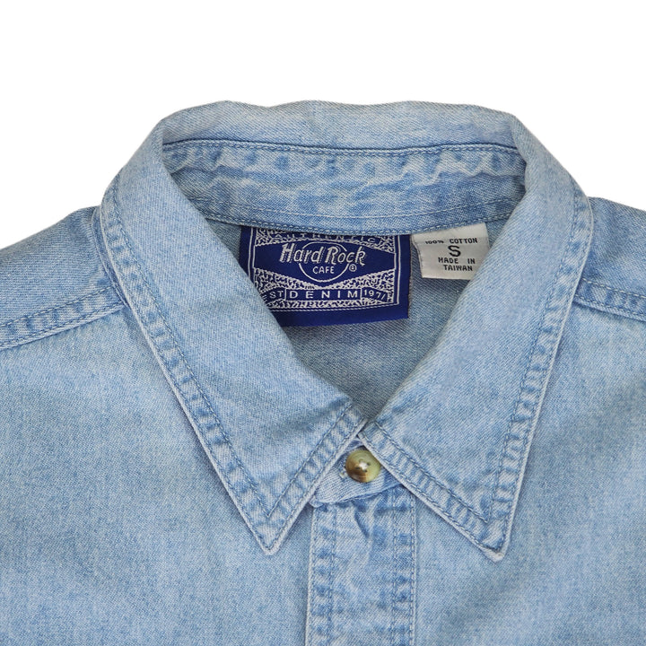 Close-up of a denim shirt collar with a Hard Rock Cafe brand label on a white background
