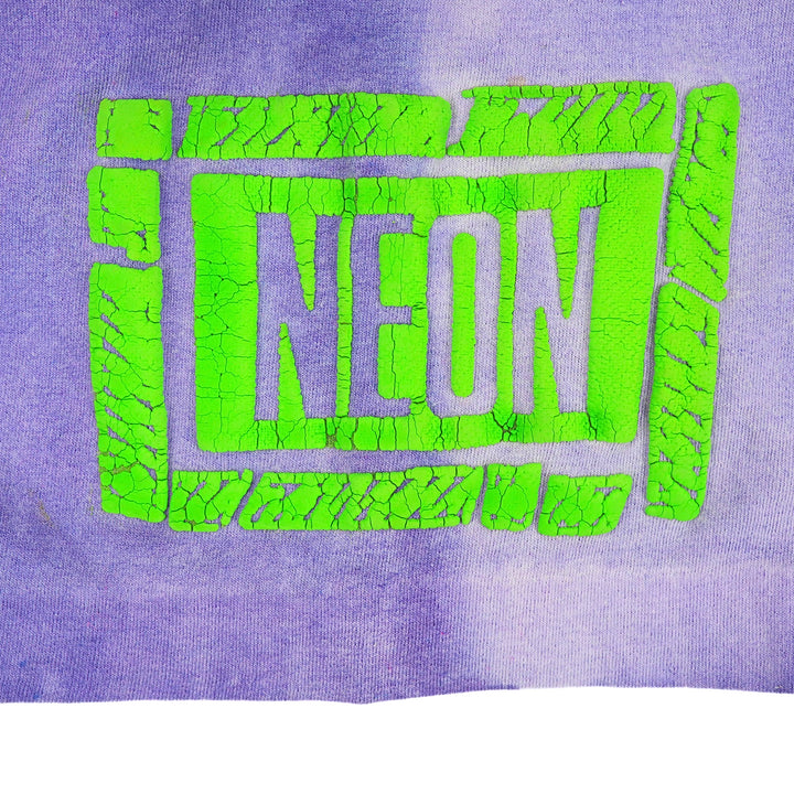 A close-up of a purple knit fabric featuring a bright neon green graphic that reads 'NEON' inside a cracked, blocky border.