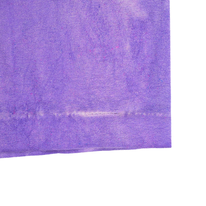 A close-up of a purple textured fabric corner with a visible stitched hem, shown against a plain white background.