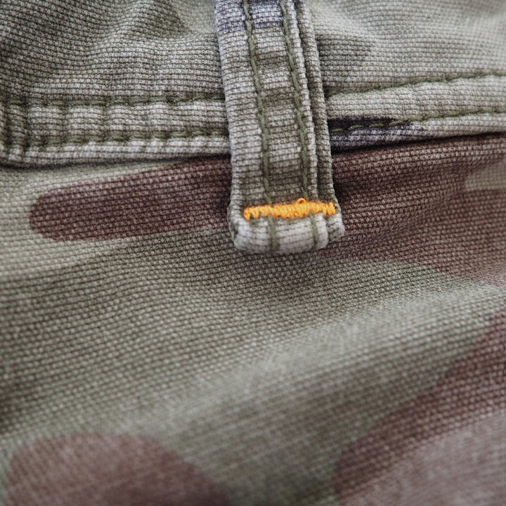 Close up of a belt loop on a pair of camouflage pants with orange stitching