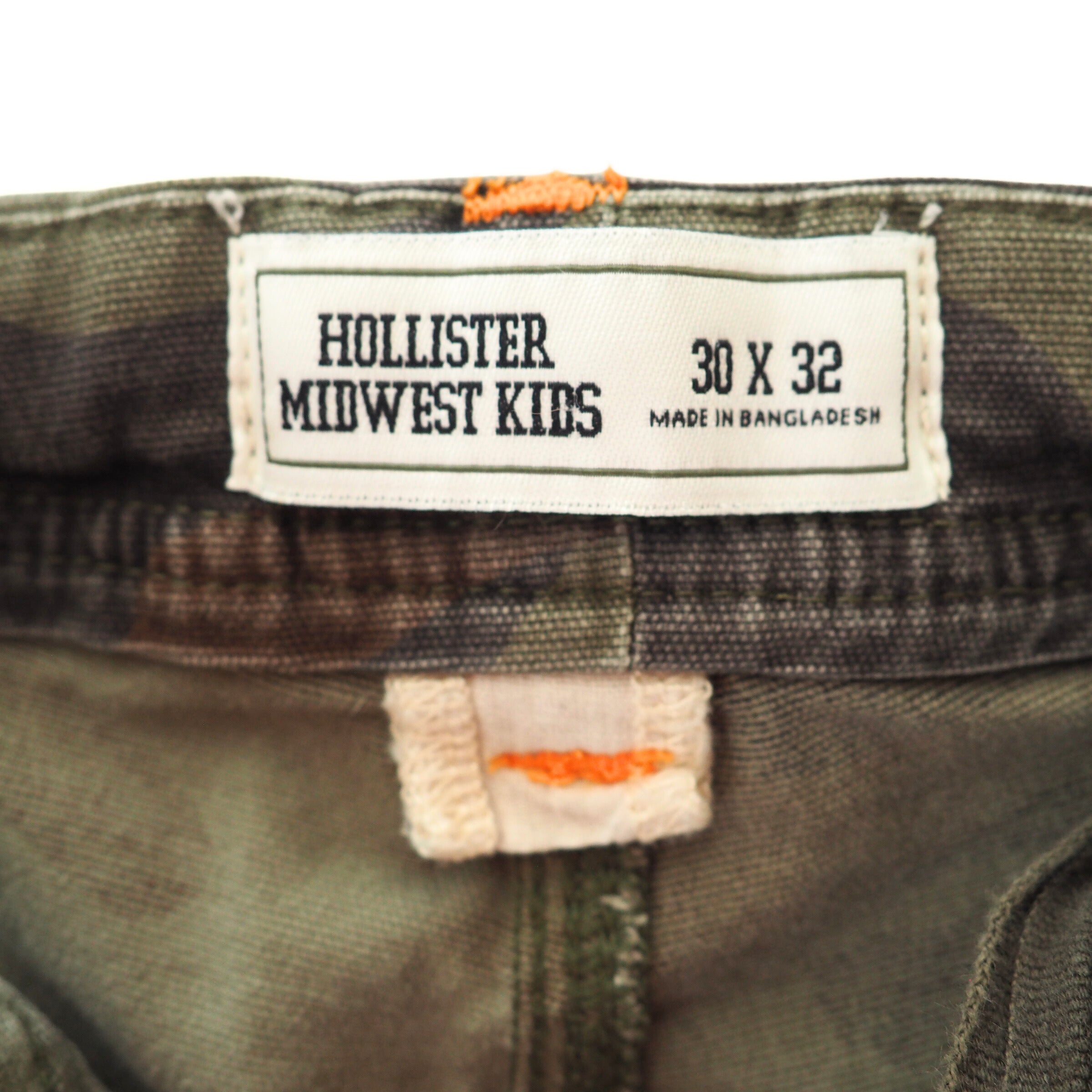 Close up of the inside waistband of a pair of camo pants with a white label and size information. 