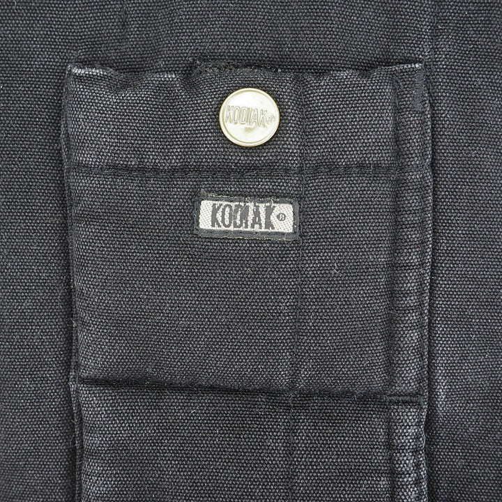 Close-up of a dark charcoal gray fabric pocket with a silver snap button and a white KODIAK brand label.