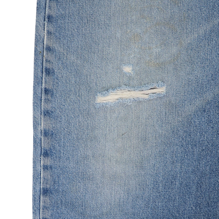 Close-up of a blue denim jeans knee area with a tear on a white background