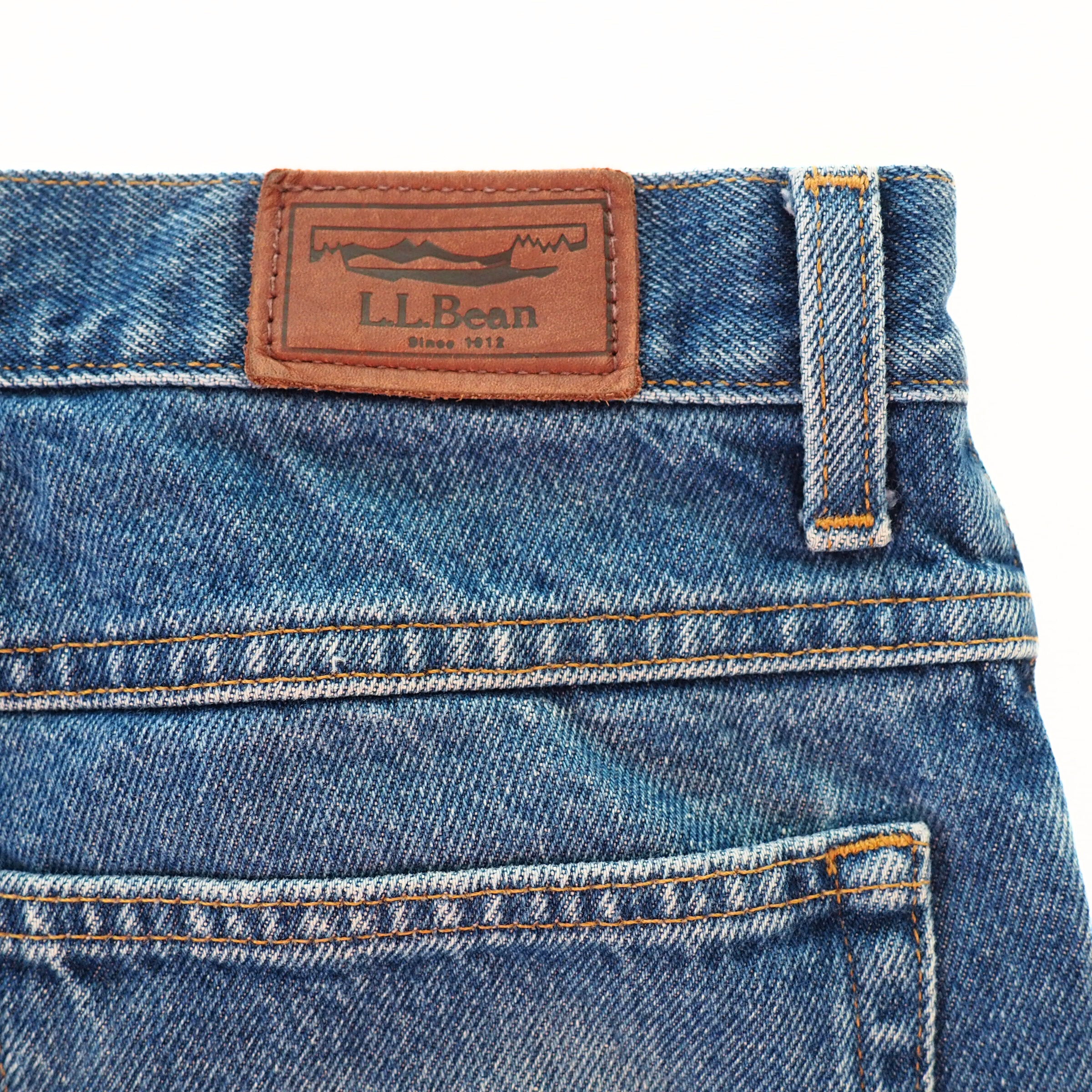 Close-up of blue jeans with a brown L.L.Bean jacron label on a white background