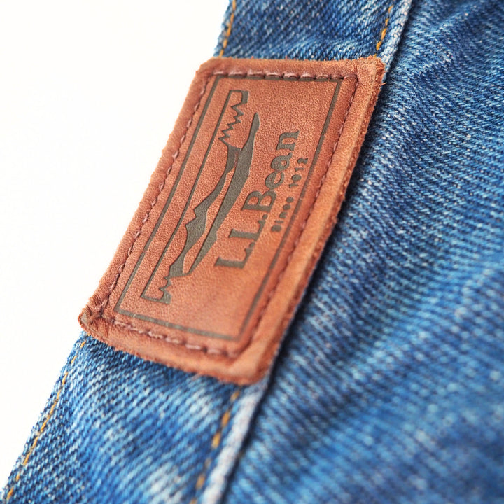 Close-up of a brown leather label on blue denim fabric, featuring the L.L.Bean logo.