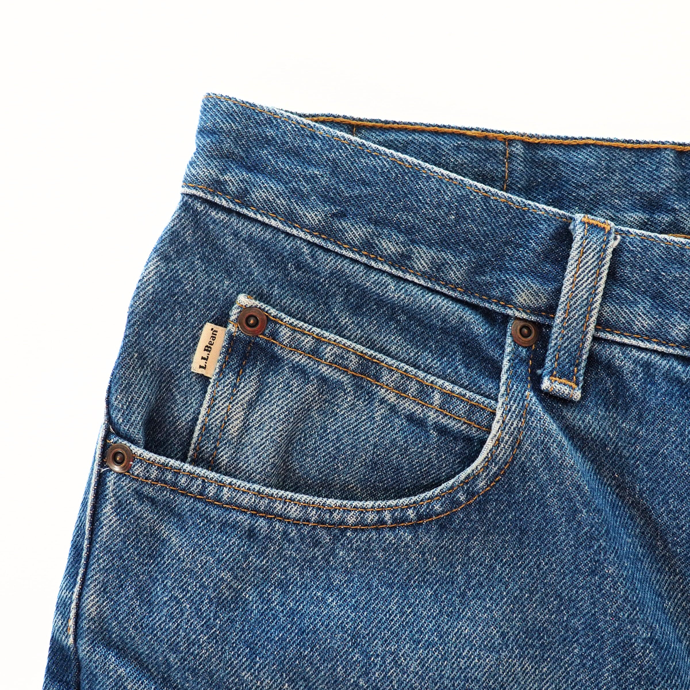 Close-up of blue jeans coin pocket with a brand label on a white background