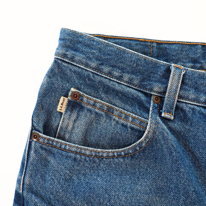 Close-up of blue jeans coin pocket with a brand label on a white background