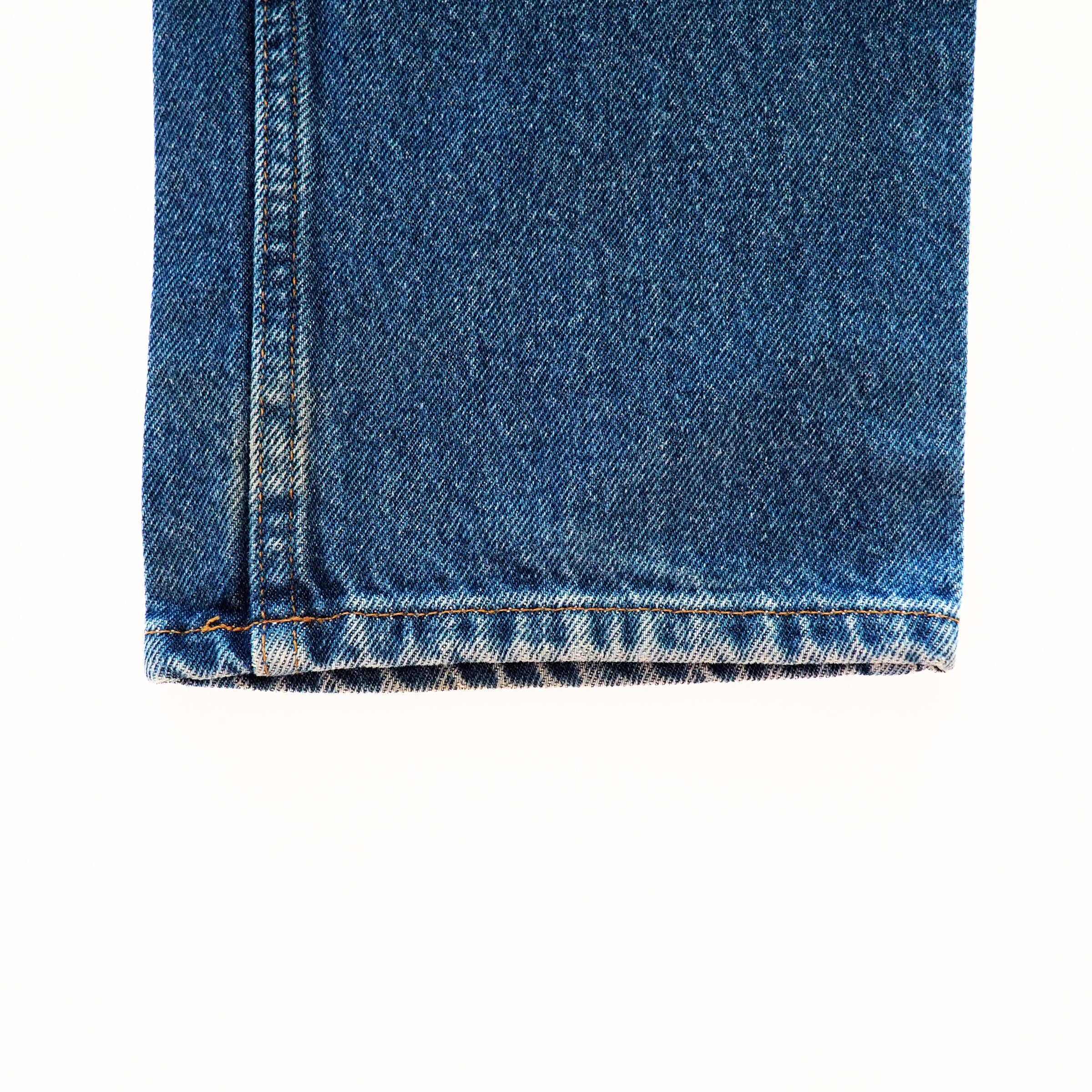 Close-up of blue denim jean pant leg cuff on a white background