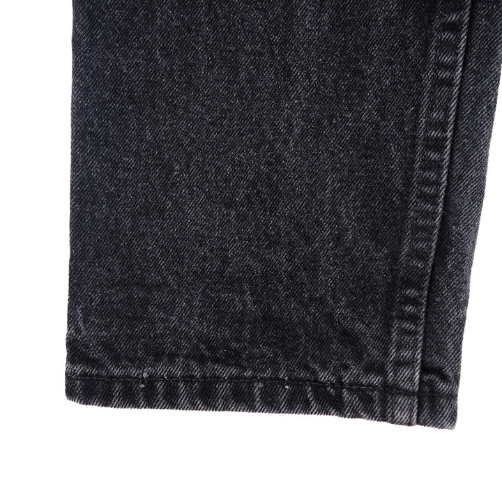 Close-up of dark gray denim jean pant leg with a white background