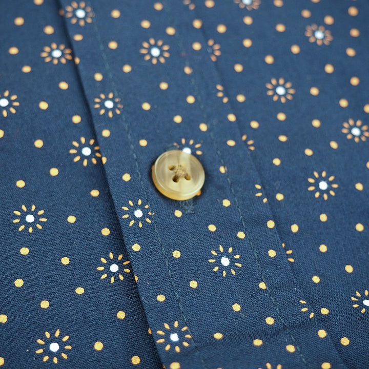 Close-up of a button on blue fabric with gold floral patterns