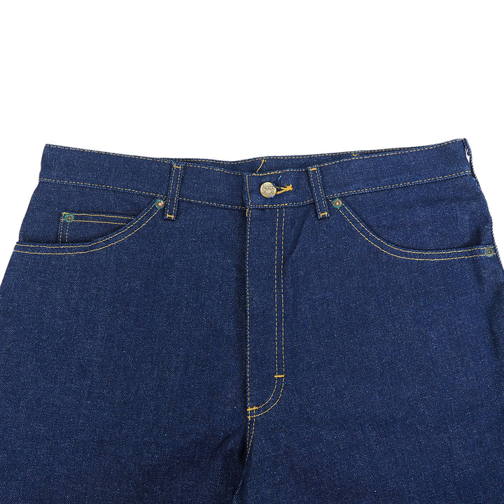 Close-up of raw indigo denim jean pants with orange stitching details on a white background