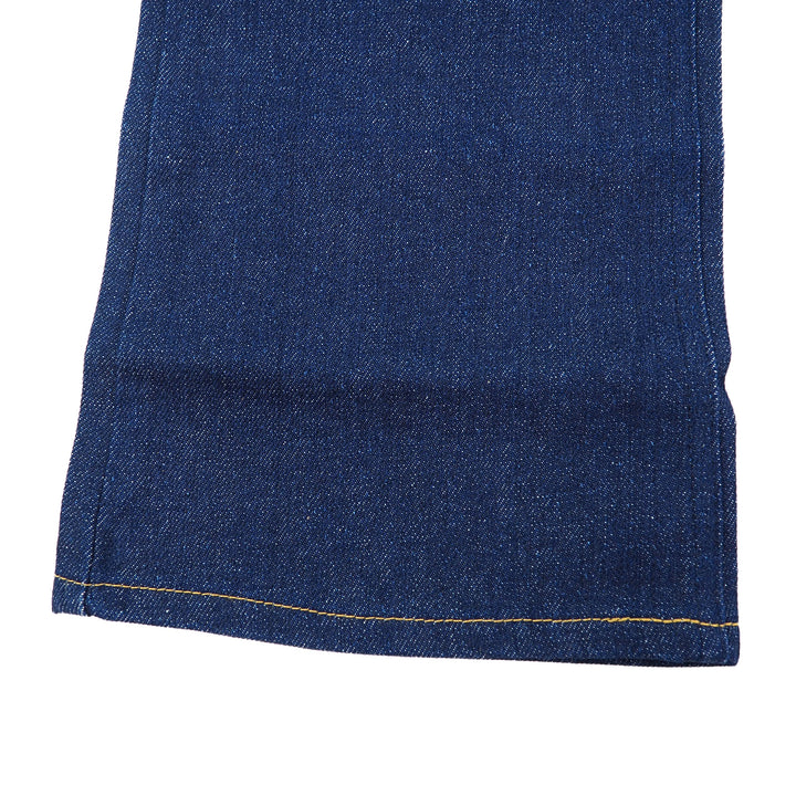 Close-up of raw indigo denim jean bootcut pant leg on a white background