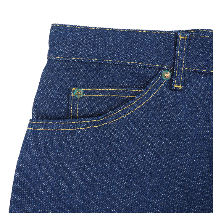Close-up of raw indigo denim jeans with rivets and stitching details on a white background