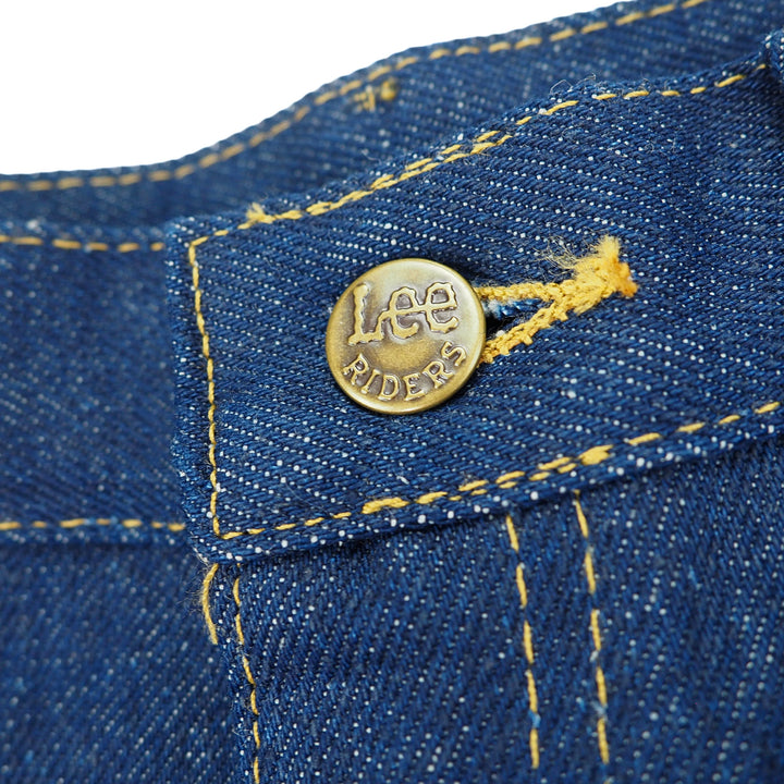 Close-up of a blue denim jeans button with 'Lee Riders' branding on a white background