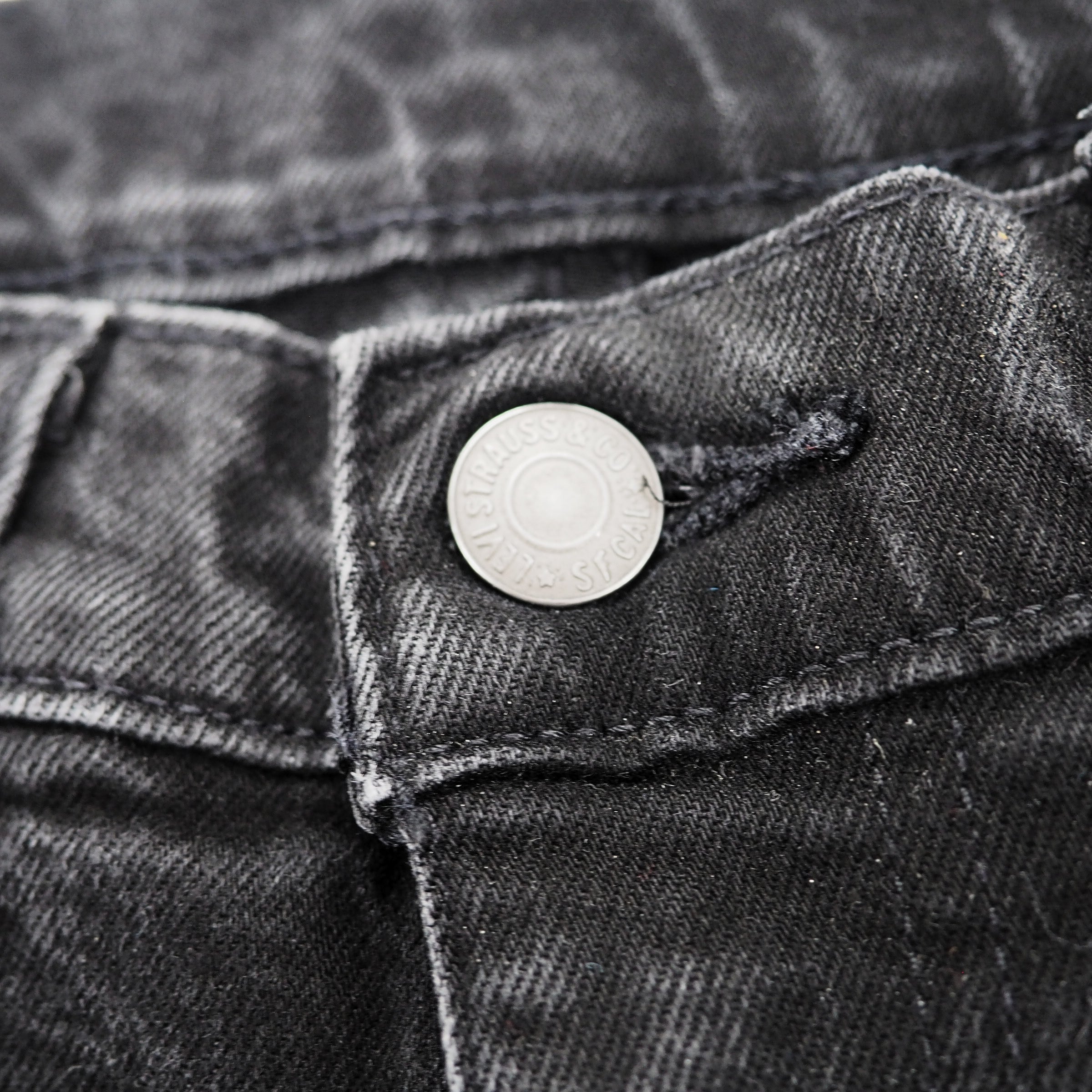 Close-up of a button on a pair of black levis jeans.