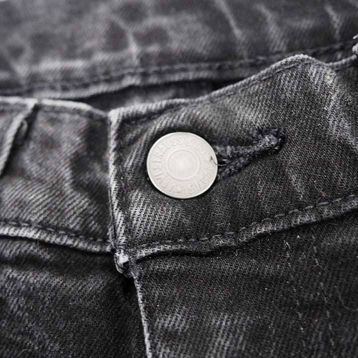 Close-up of a button on a pair of black levis jeans.