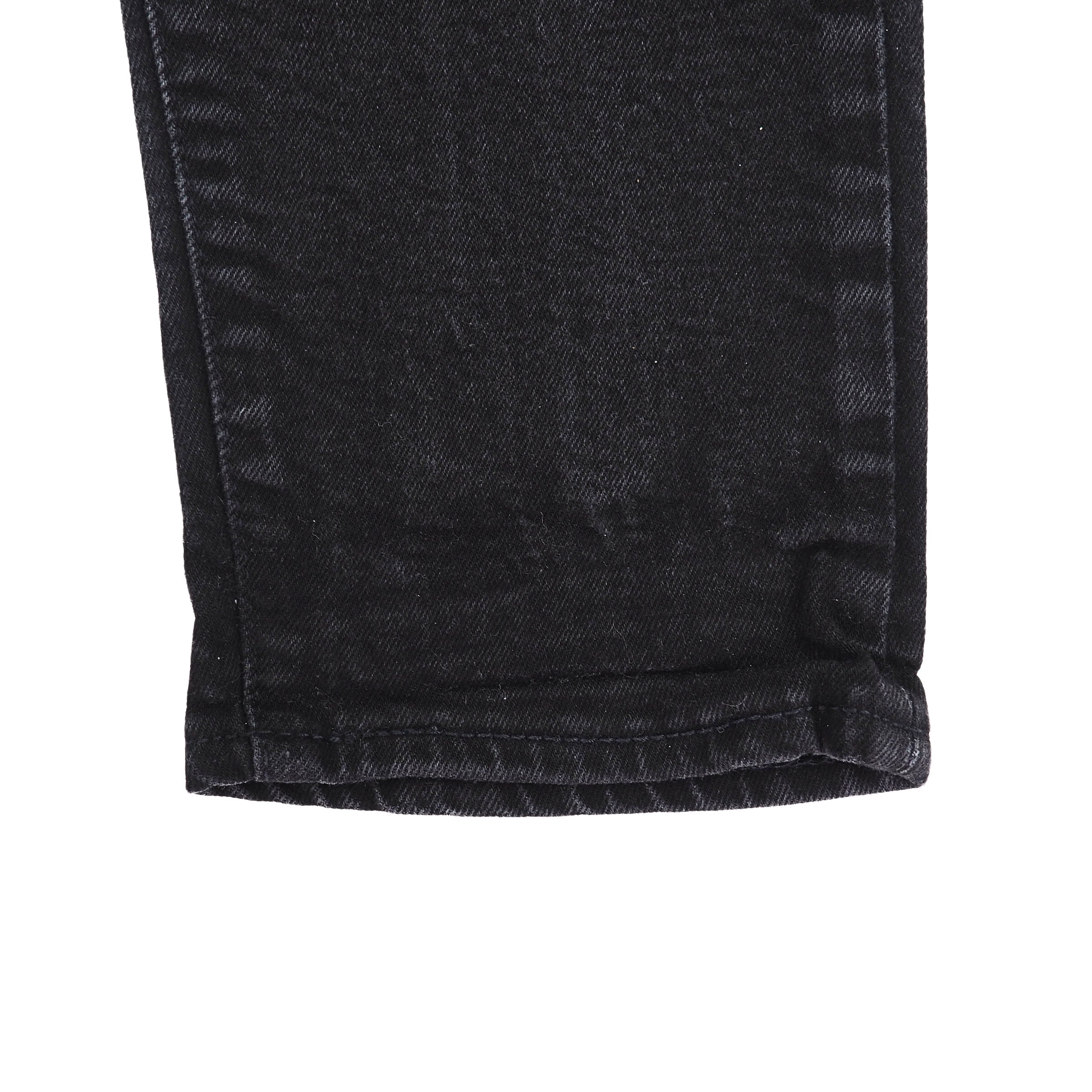 Close-up of black denim jeans ankle cuff with a white background