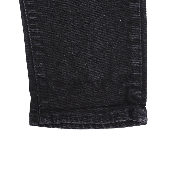 Close-up of black denim jeans ankle cuff with a white background