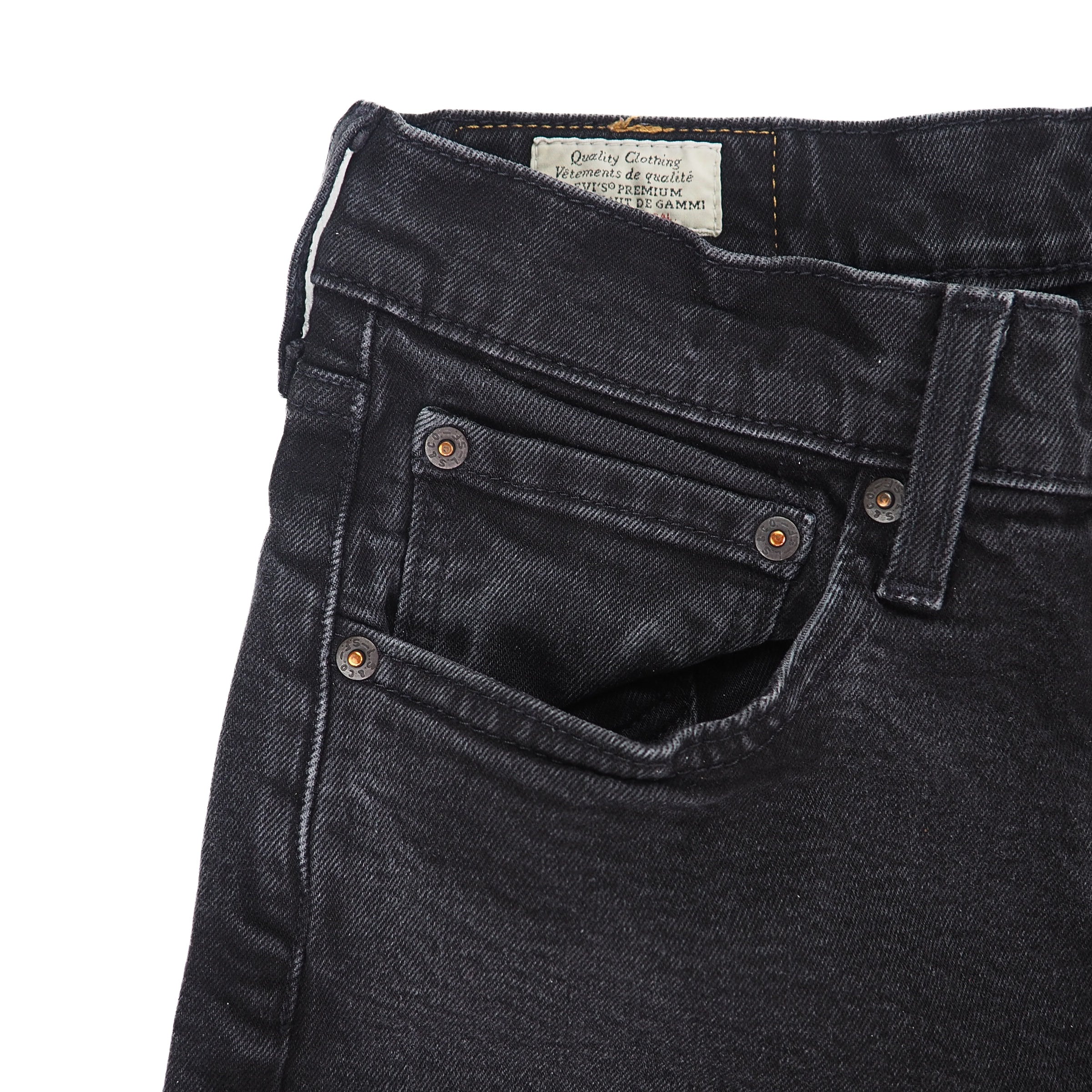 Close-up of black levis jeans with a visible brand label on a white background