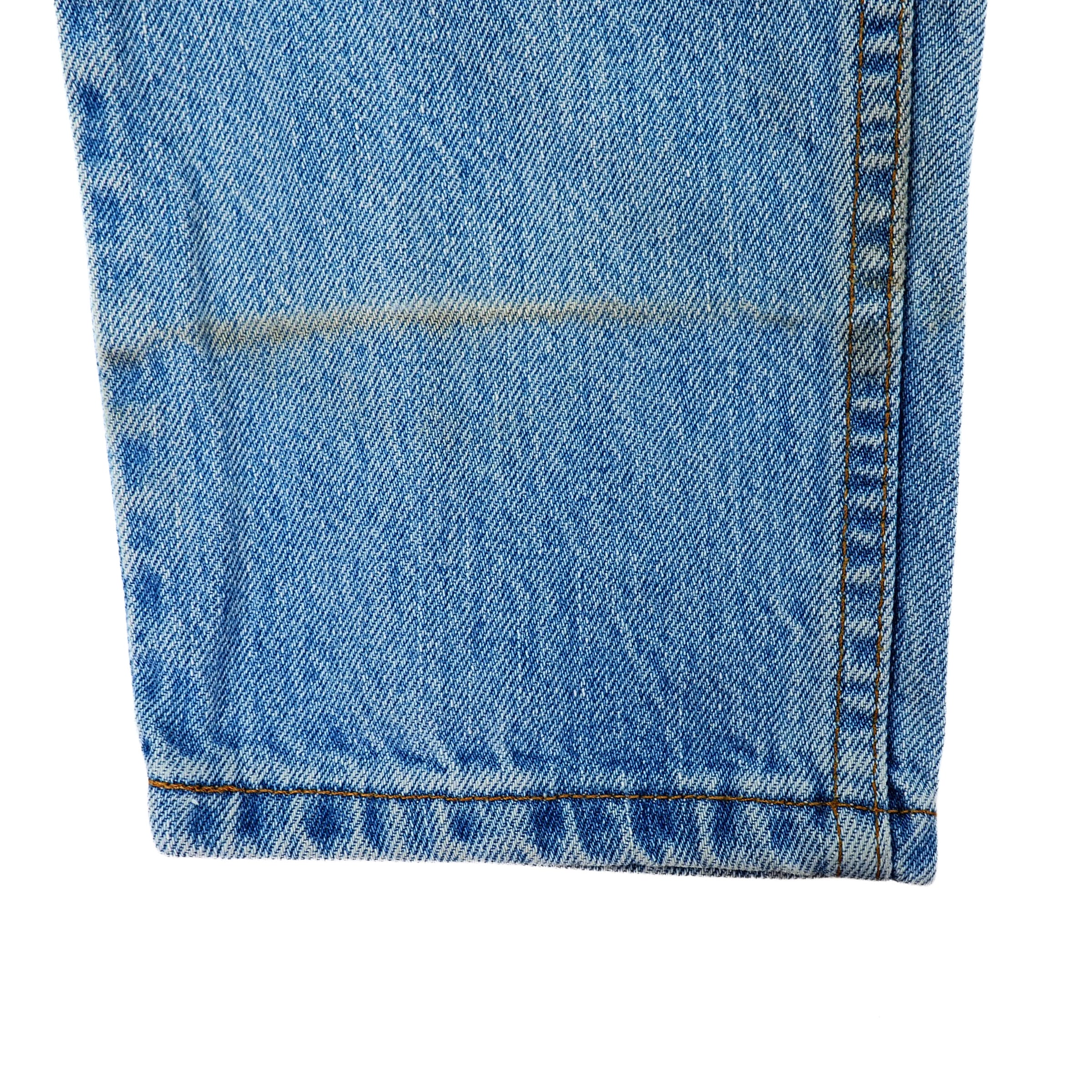 Close-up of blue denim jean pant leg with a white background