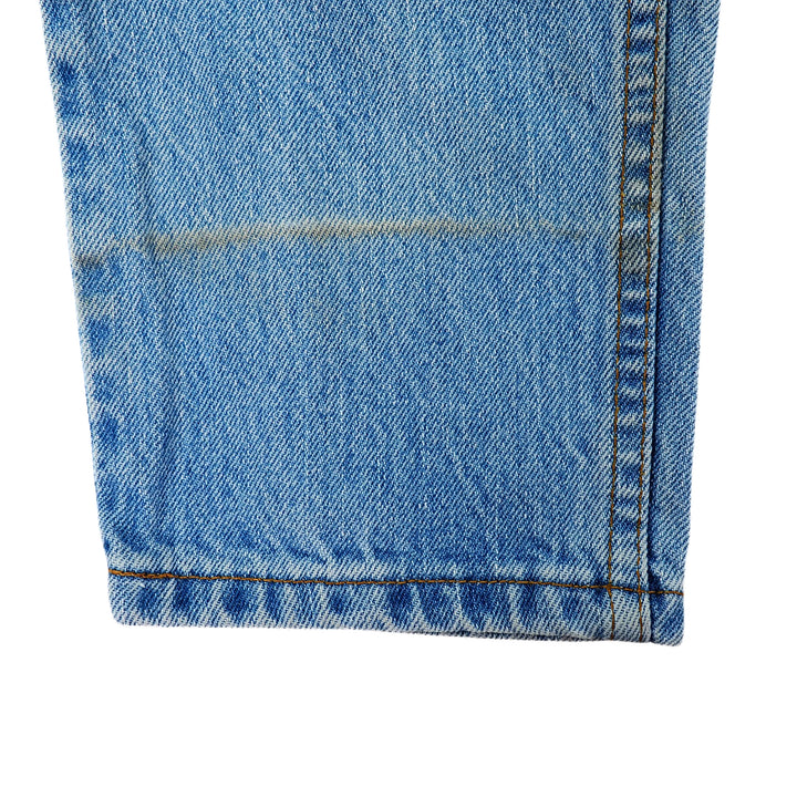 Close-up of blue denim jean pant leg with a white background