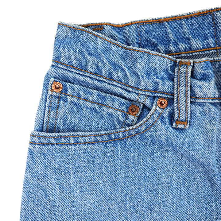 Close-up of blue denim jeans coin pocket area with rivets and stitching details on a white background