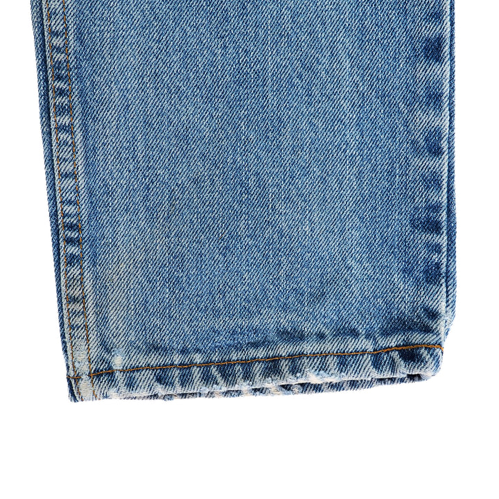Close-up of blue denim jeans pant leg ankle cuff with a white background