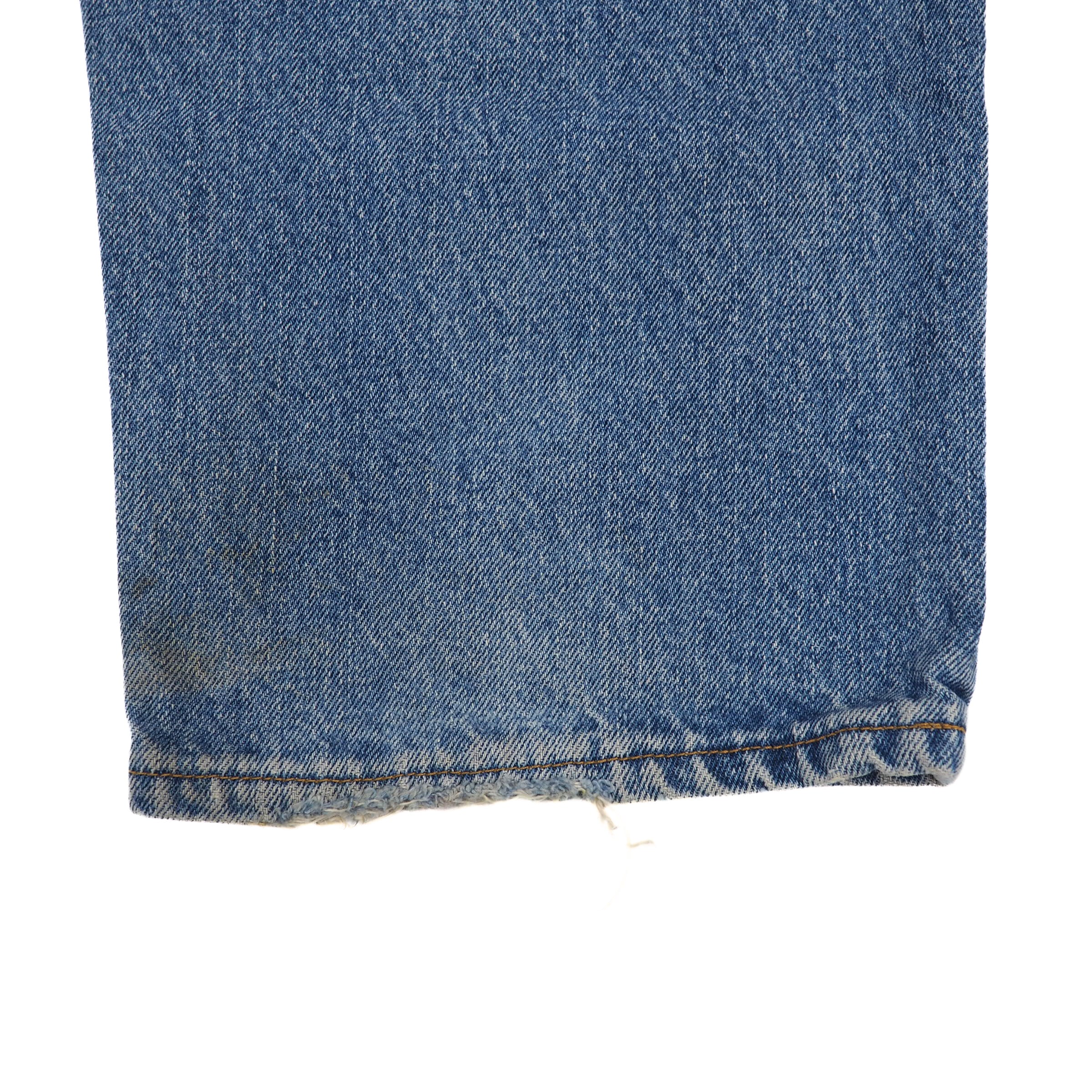 Close-up of blue denim jean pant leg cuff on a white background
