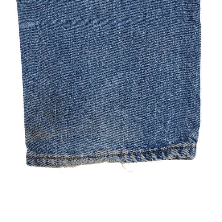 Close-up of blue denim jean pant leg cuff on a white background