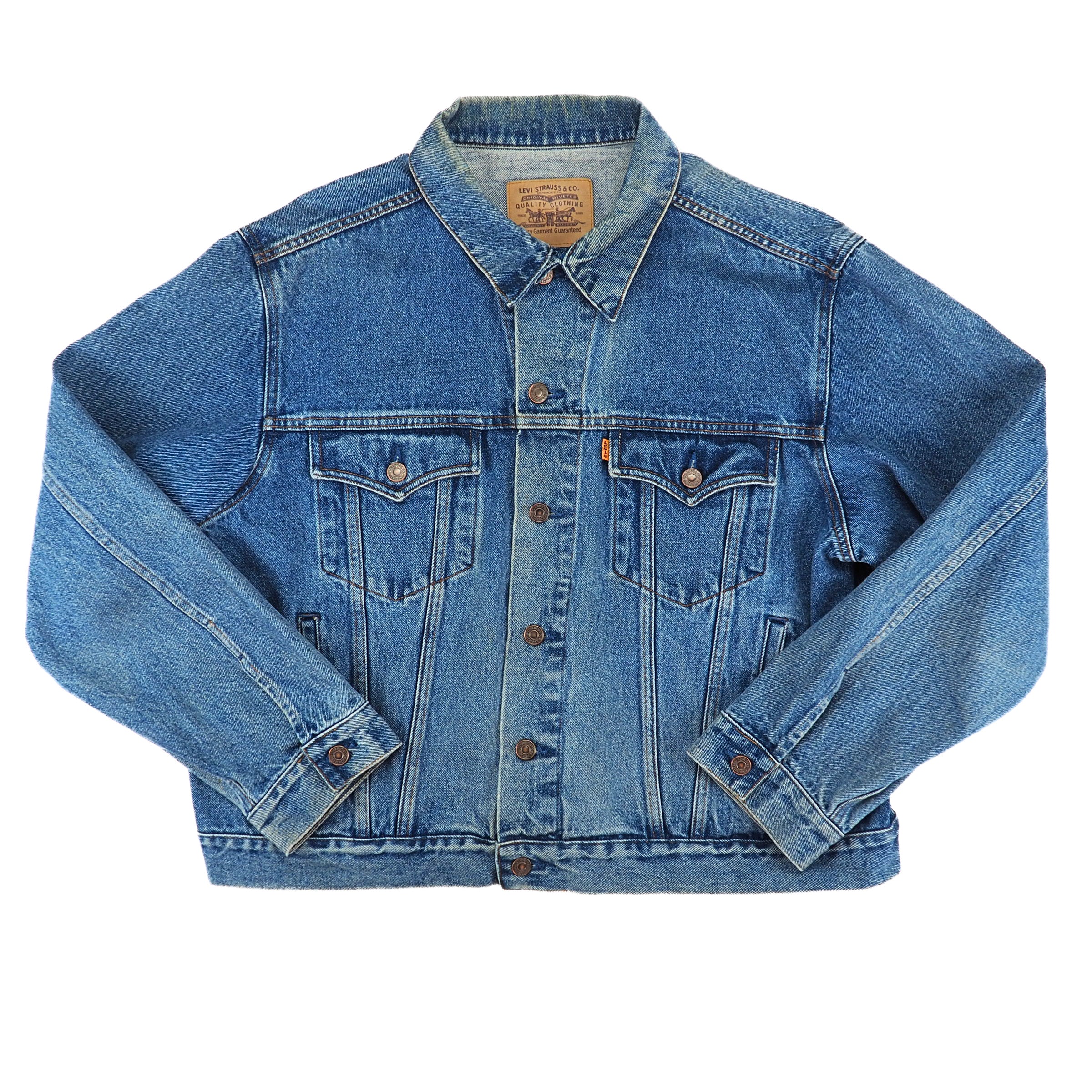 A classic medium-wash blue denim trucker jacket with button-front closure, chest flap pockets, and buttoned cuffs, laid flat against a white background.