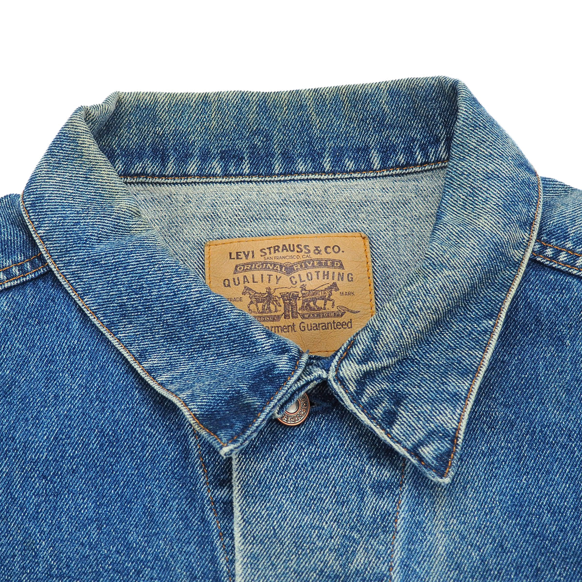 Close-up of a blue denim shirt collar with a visible Levi's brand patch inside the neck, on a plain white background.
