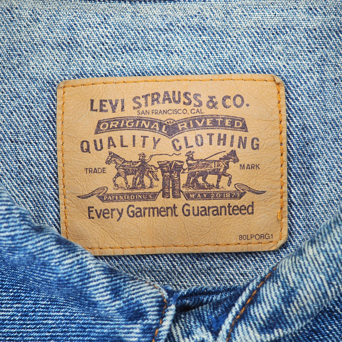 Close-up of a Levi's leather brand patch sewn onto blue denim fabric.