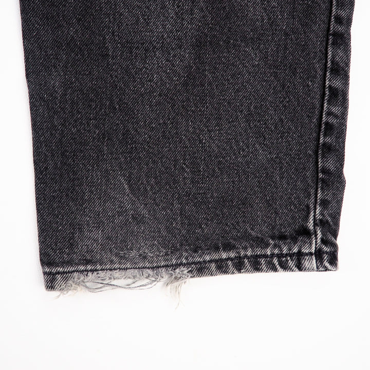 Close-up of a black denim fabric with frayed edge on a white background