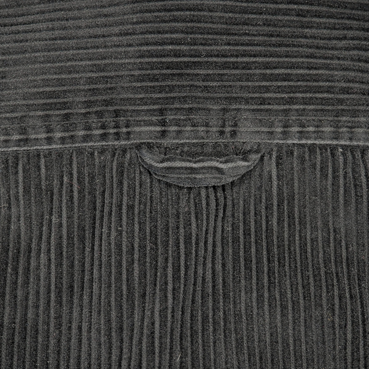 Close-up of a dark charcoal gray corduroy fabric with a small curved coat hook loop detail.
