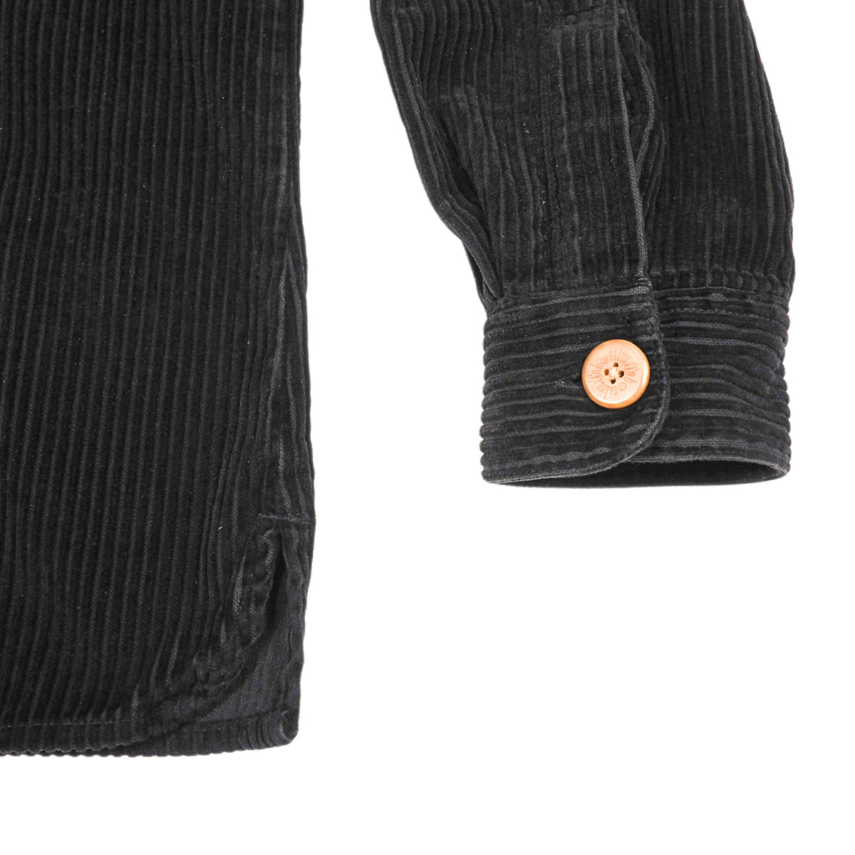 Close-up of a black corduroy garment, showing the ribbed fabric texture and a single round tan button on the cuff, against a plain white background.