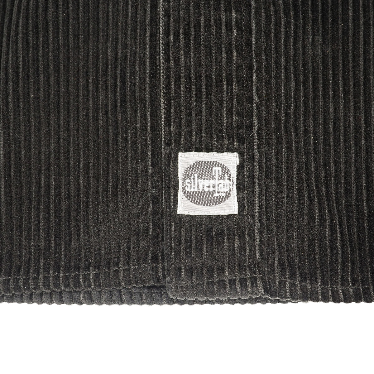 Close up of a silverTab label on the placket of a black corduroy shirt.